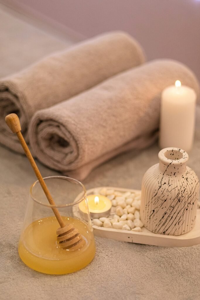 a table topped with candles and towels next to a jar of honey a table topped with candles and towels next to a jar of honey